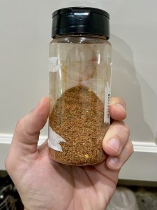 A reused spice jar containing a mix of herbs and spices. 