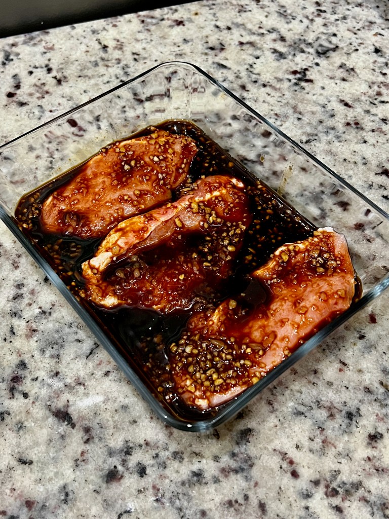 Three pork chops soaking in marinade. 
